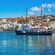A traditional Greek boat moored seaside next to a rambling village
